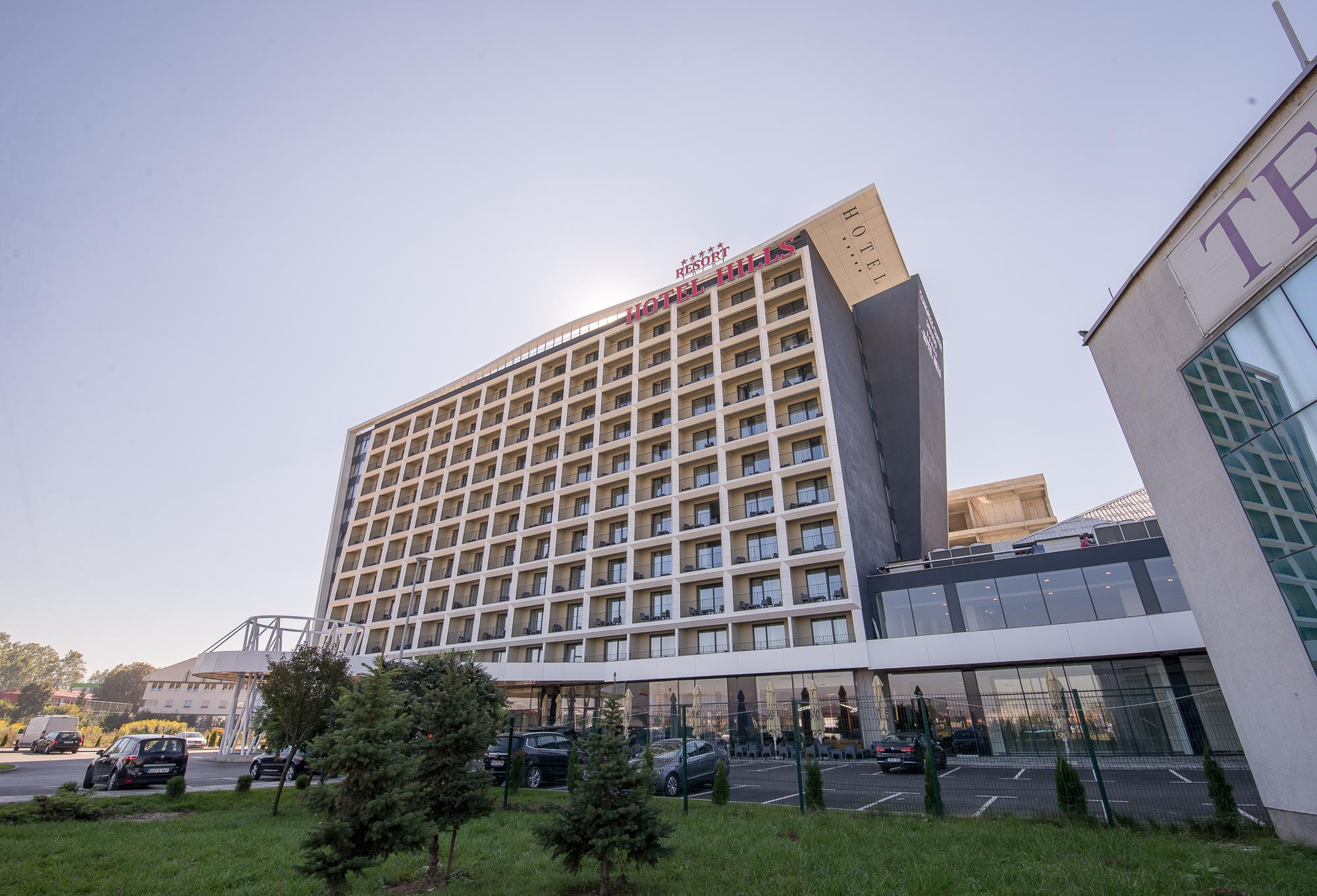 Hotel Hills Sarajevo Congress & Thermal Spa Resort Exterior photo The photo shows a modern hotel building with multiple floors and a contemporary design. The structure features large windows arranged in a grid pattern and a prominent entrance area at the bottom. There are green areas, possibly with trees or landsca